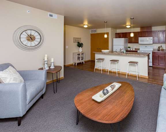 a living room with a couch and a table in front of a kitchen at Melbourne Apartments, Des Moines, IA,  50320