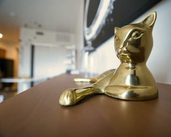 A golden cat sculpture sits on a wooden table.