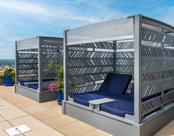 Two beds with blue pillows and grey striped headboards.