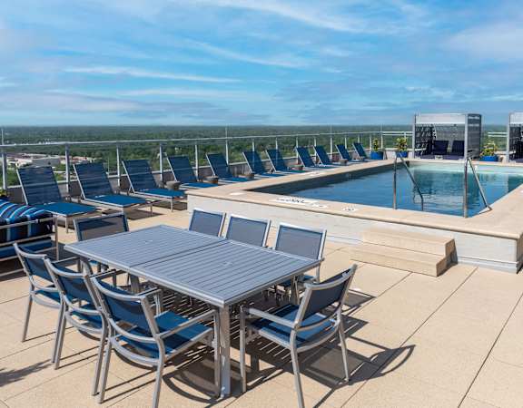 A table and chairs are set up on a patio overlooking a pool.