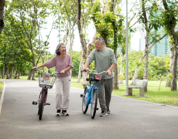 An older couple on a bike path in a park.