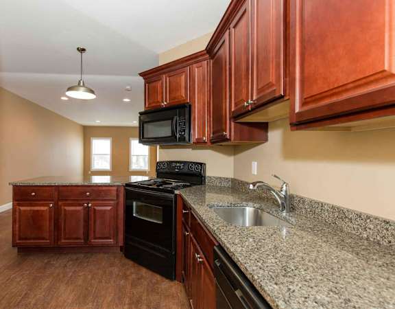 A kitchen with brown cabinets and granite countertops.
