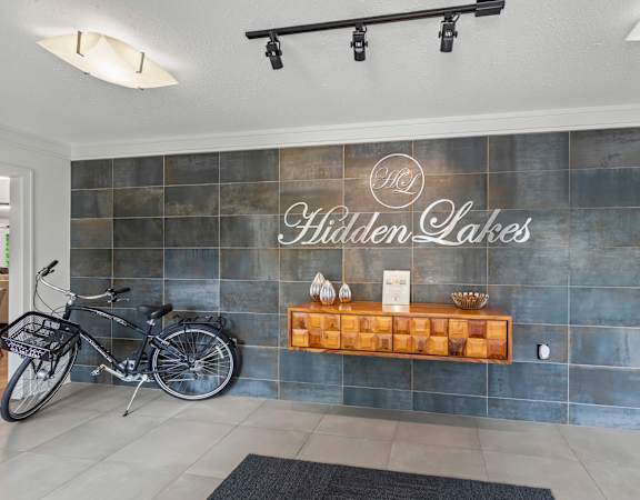 A bicycle is parked in front of a wall with a sign that reads "Hidden Lakes.".