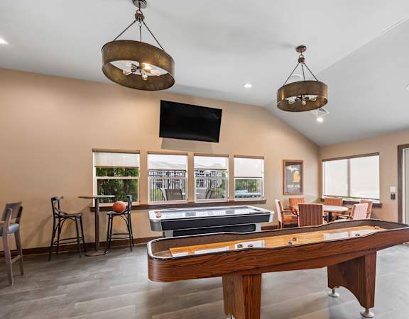 A billiard table is in the middle of a room with a television and a pool table.