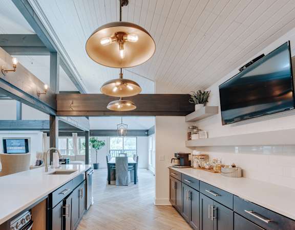 A modern kitchen with a large island and a flat screen TV mounted above it.