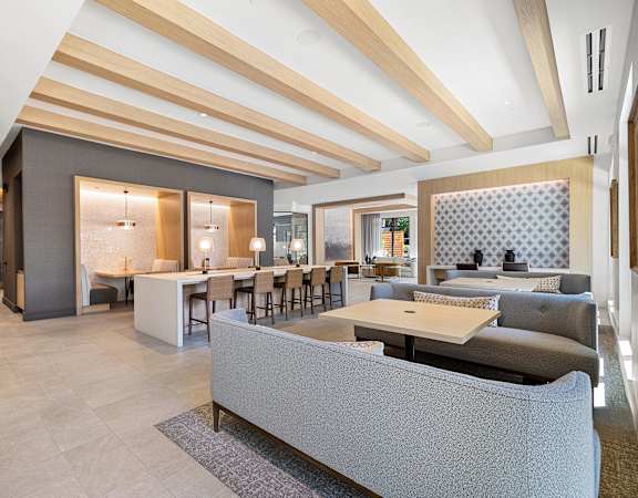 Resident lounge with flexible seating, work tables, and a warm inviting atmosphere
