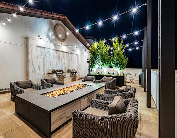 Rooftop terrace with fire pit lounge, string lights, and plush seating designed for cozy evenings