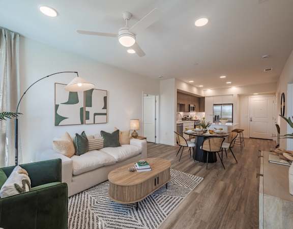 Furnished living and dining area with wood-style flooring, large windows, and an open kitchen.