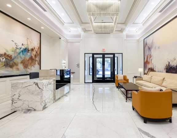 the lobby of a hotel with couches and a marble reception desk