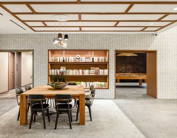 a dining room with a wooden table and chairs and a book shelf