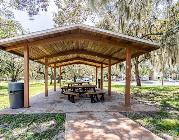 a picnic pavilion with benches and tables in a park