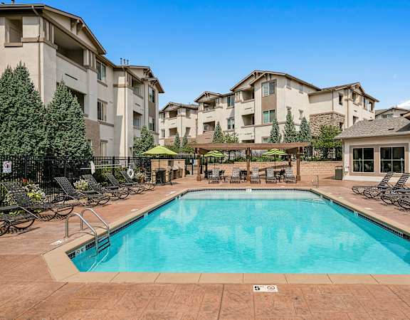 Resort-style swimming pool with ample lounge seating - First and Main Apartments