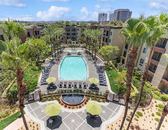 A pool surrounded by palm trees and umbrellas at The Kitt at Warner Center in CA, 91303