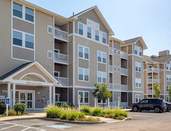 an exterior view of an apartment building with a parking lot at Rosemont Square Apartments, Massachusetts, 02368