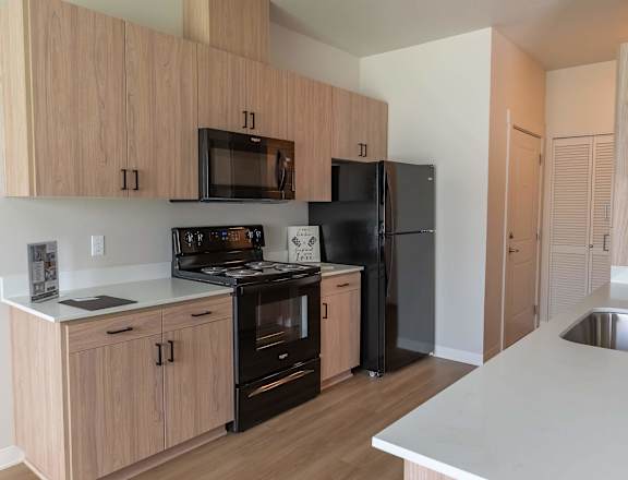 A kitchen with wooden cabinets and black appliances at Cascade Place Apartment Homes, Molalla, OR, 97038