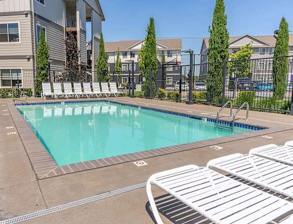 A swimming pool surrounded by white lounge chairs at Timberridge Place Apartment Homes, Albany, 97322