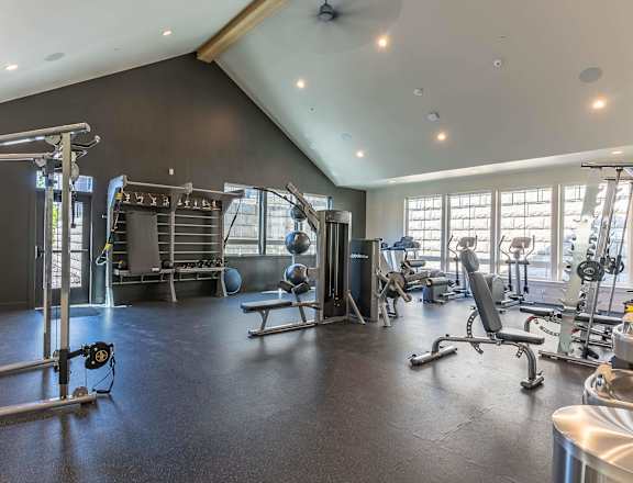 A spacious gym with a variety of equipment including a squat rack, bench, and weights at Westgate Apartment Homes, Pendleton, OR, 97801