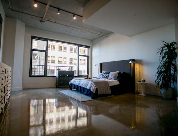 a bedroom with a bed and a large window in a loft at Garment Lofts, California