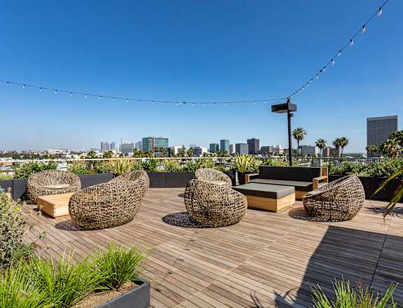 A roof deck with seating and a view of the los angeles skyline at Mariposa on 3rd, Los Angeles, CA 90004