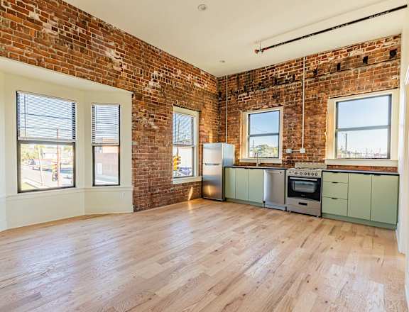 an empty living room with a brick wall and wood floors
