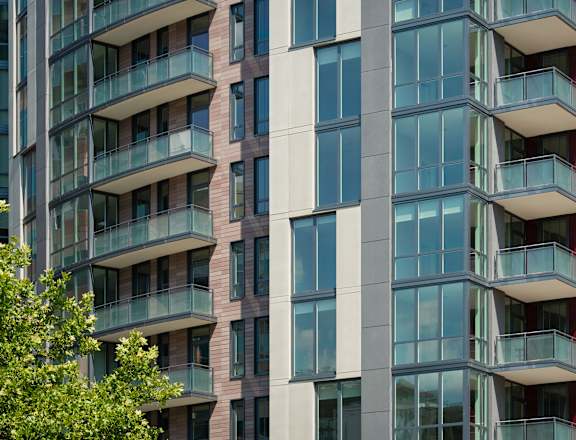 a city building with balconies and trees in the foreground