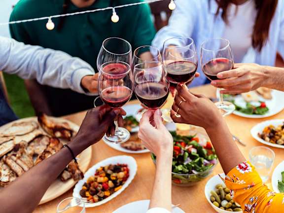 Group of people toasting with wine glasses at a dinner table at Brea Grove Residences Apartments, California