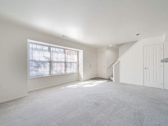 an empty living room with white walls and a large window
