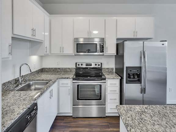 a kitchen with white cabinets and granite counter tops and stainless steel appliances at Aviara Apartments, San Jose