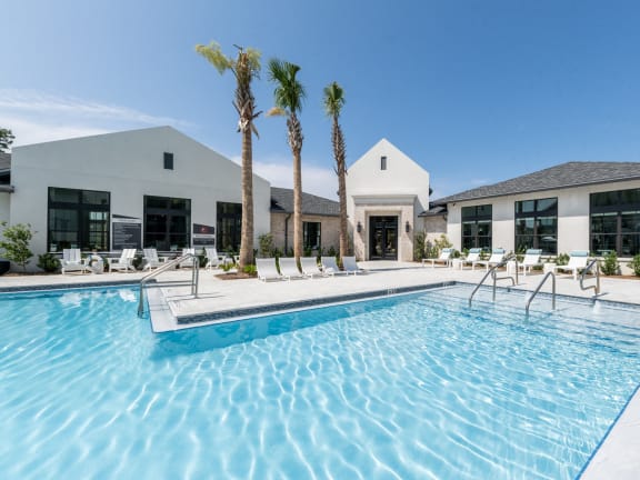 a swimming pool with palm trees in front of a house at Residences at 393 North Apartments, Santa Rosa Beach, FL