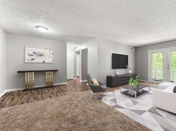 A living room with a white couch, a coffee table, and a television at Bradford Gwinnett Apartments and Townhomes in Norcross, GA