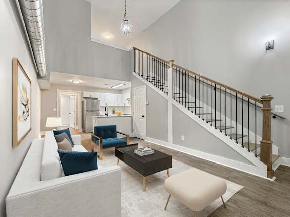 A living room with a staircase and a couch at Crogman School Lofts in Atlanta, GA, 30315