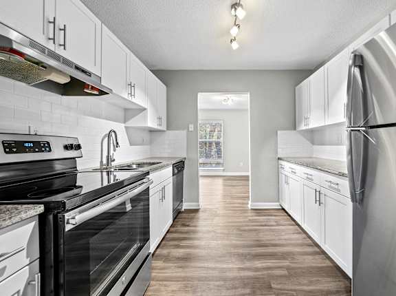 A modern kitchen with white cabinets and stainless steel appliances.