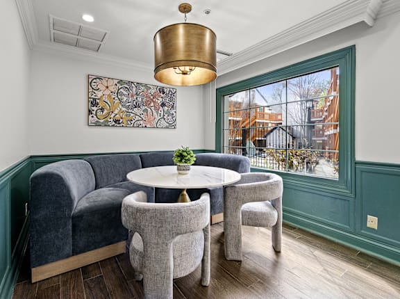 A room with a grey couch, a small table and a chandelier.