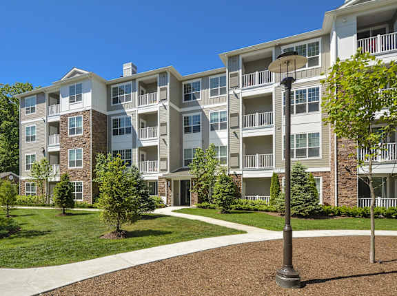 A large apartment complex with a well-maintained lawn and trees.