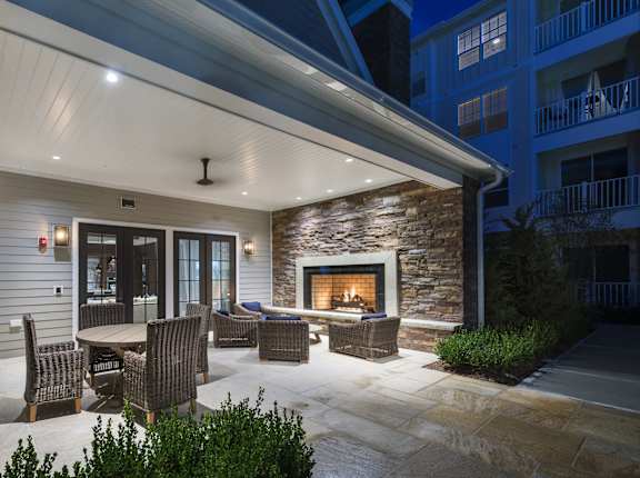 A patio with a fireplace and chairs is lit up at night.