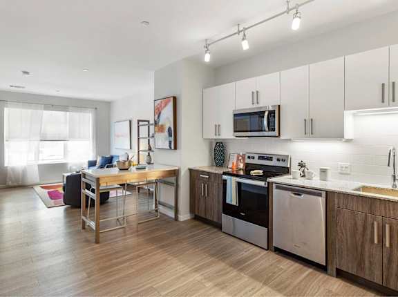 A modern kitchen with wooden floors and stainless steel appliances.