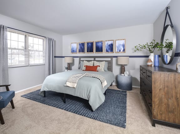 A bedroom with a bed, a dresser, and a mirror.