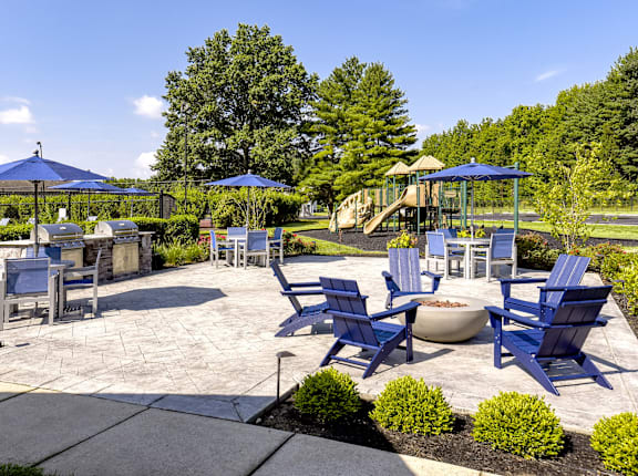 A sunny day at the park with blue chairs and umbrellas.