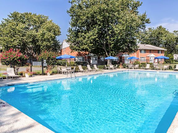 A large blue swimming pool surrounded by trees and a fence.
