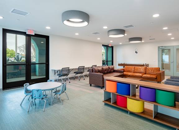 A conference room with a white table and chairs, a couch, and a TV.