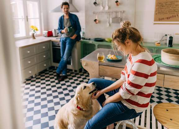 a woman is petting a dog in a kitchen