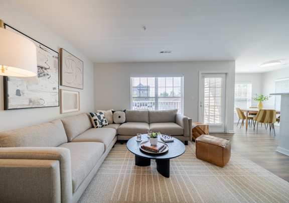 A living room with a grey couch, a white chair, a black table, and a television.