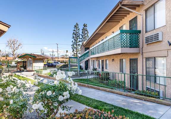 A building with a green fence and white flowers in front. at Heritage Park, Rialto, 92376