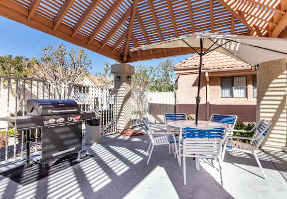 A patio with a grill and chairs under a wooden roof. at Whispering Fountains Diamond Bar, Diamond Bar California
