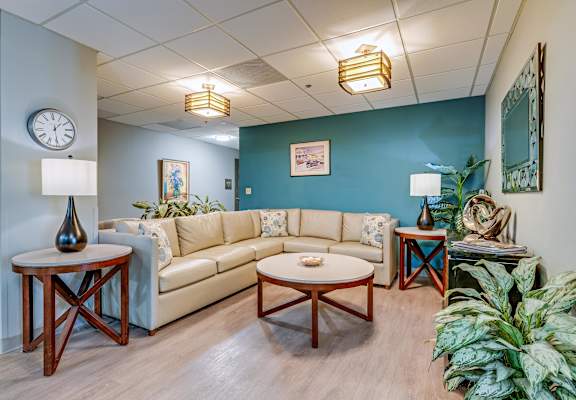 A living room with a couch, coffee table, and plants.