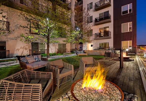 A fire pit in the middle of a patio surrounded by chairs.