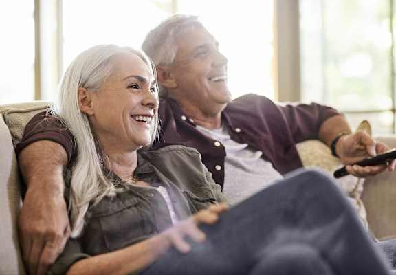 a man and woman sitting on a couch with a remote control