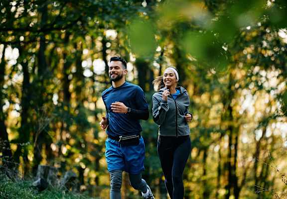 Two people running in a forest.