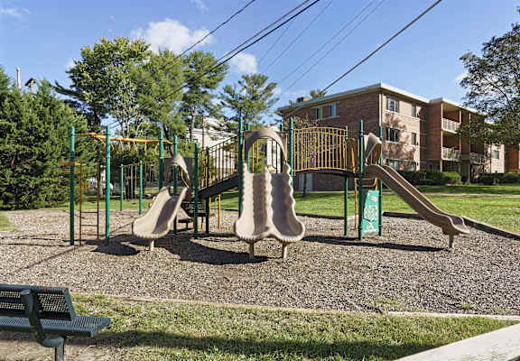 A playground with a slide, swings and a bench.