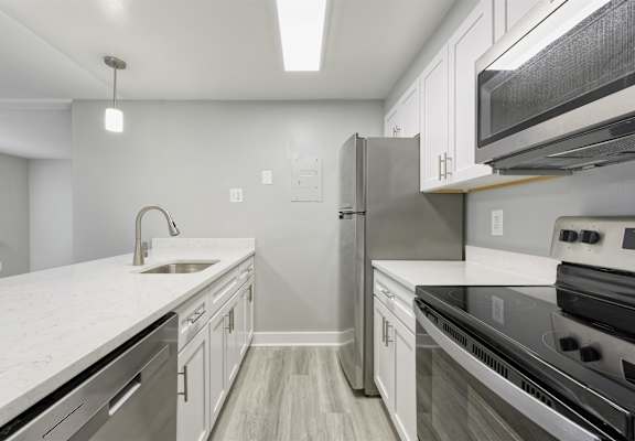 A modern kitchen with stainless steel appliances and white countertops.